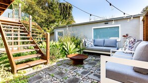 A patio with a wooden staircase, a gray sofa, and a coffee table. - Idyllic 4-Bed Home With Alfresco Area Near Beach (Dee Why)