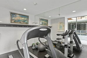 Un gimnasio con cintas de correr, pelotas de ejercicio y un espejo grande.