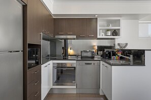 Una cocina moderna con electrodomésticos de acero inoxidable, armarios blancos y horno empotrado.