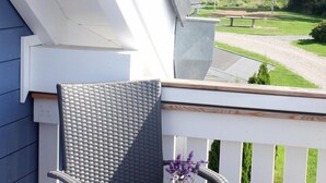 Varanda com mesa posta para o café da manhã, vista para o mar e um veleiro ao longe.