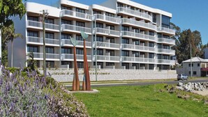 A multi-story hotel with balconies, a landscaped garden, and a parking area. - Elegant 2-Bed Apartment with Incredible Bay Views (Batemans Bay)