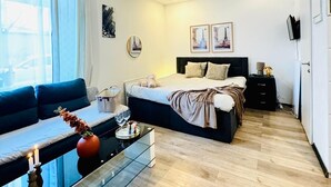 Een moderne slaapkamer met een bed, nachtkastjes, een bank en een glazen salontafel.