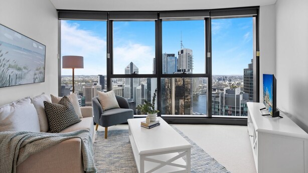 Ein modernes Wohnzimmer mit großem Fenster, einer Couch, einem Couchtisch und einem Fernseher.