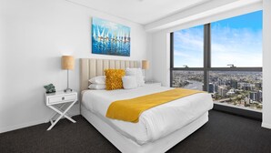 Ein modernes Hotelzimmer mit einem großen Bett, Blick auf die Stadt und einem Gemälde an der Wand.
