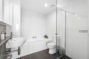 Ein modernes Badezimmer mit Waschbecken, Badewanne und Toilette, ausgestattet mit einer Duschkabine aus Glas.