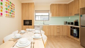 Una cocina moderna con armarios de madera, una mesa de comedor preparada para cuatro personas y una decoración de pared colorida.