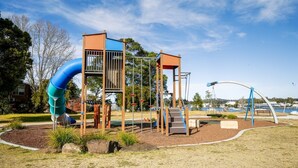Un parque infantil con un tobogán, estructuras para escalar y columpios.
