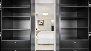A bedroom with a bed, a nightstand, a framed picture, and a wardrobe with multiple shelves. - Comfy 2-Bed Apartment with A/C throughout (Manly)