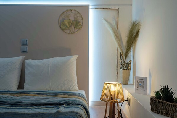 A neatly made bed with striped bedding, a bedside lamp, and a wall-mounted decorative item.