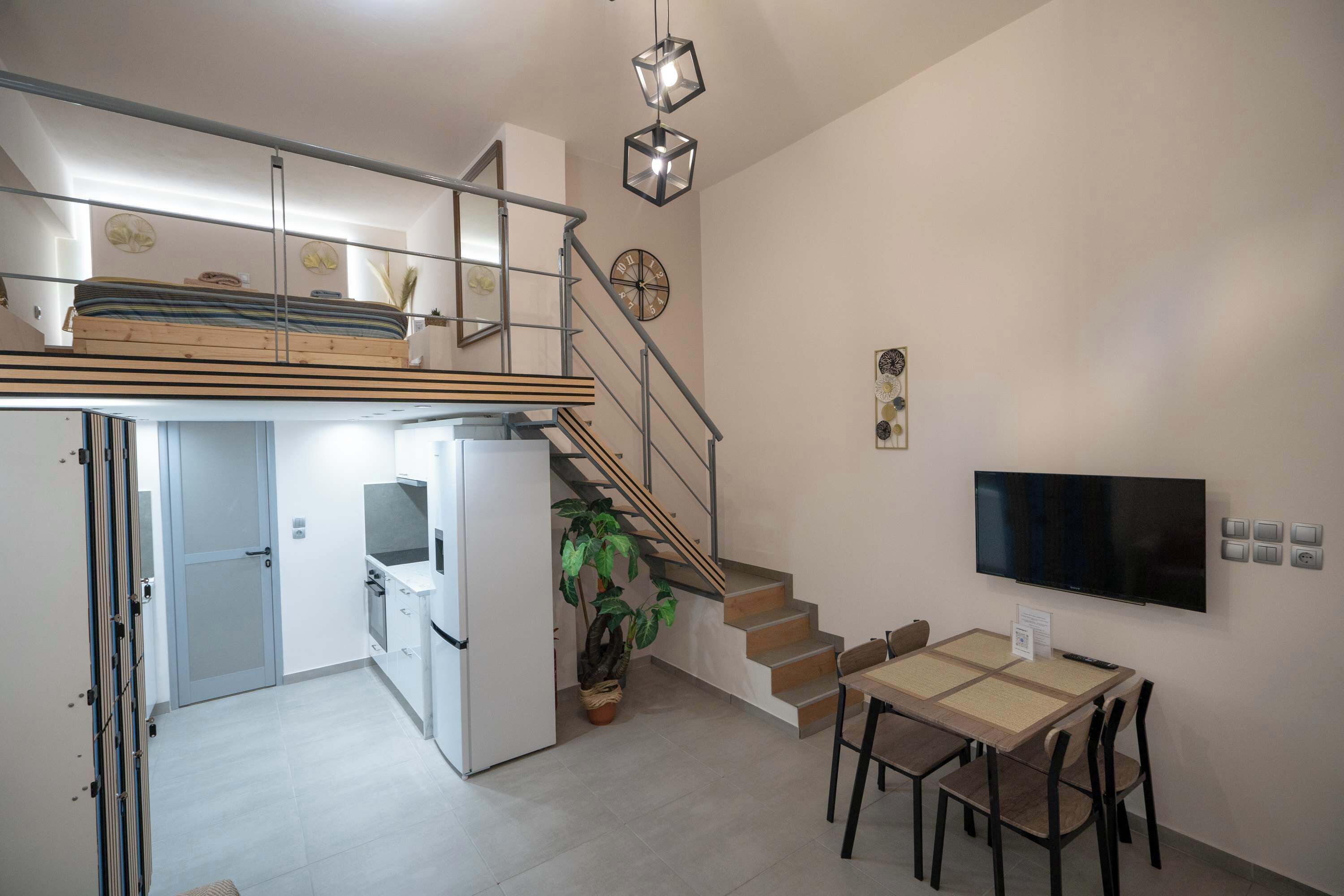 Un apartamento moderno con cocina, comedor y una escalera que lleva a un dormitorio tipo loft.