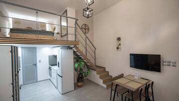 Un apartamento moderno con cocina, comedor y una escalera que lleva a un dormitorio tipo loft.