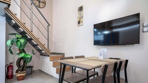 A modern hotel room with a dining area, a flat-screen TV mounted on the wall, a staircase, and a potted plant. - Loft 53 – Twin Loft II by ΜΡS (Athens)