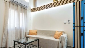 A room with a sofa, a glass table, a blue wardrobe, and a curtain. - Loft 53 – Twin Loft II by ΜΡS (Athens)