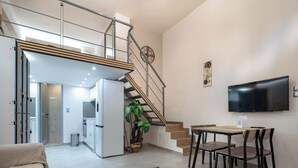 A modern living space with a staircase, a dining area, a TV, and a kitchen. - Loft 53 – Twin Loft II by ΜΡS (Athens)