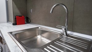 A modern kitchen with a stainless steel sink, a red appliance, and a marble countertop. - Loft 53 – Twin Loft II by ΜΡS (Athens)