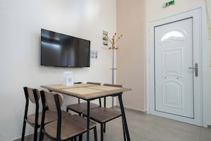 Una habitación con un televisor de pantalla plana montado en la pared, una puerta blanca y una mesa con sillas.