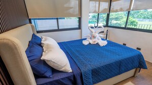 Un lit avec une literie bleue, un oreiller blanc et une serviette ornée d’un logo.