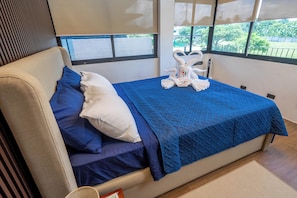 A bed with blue bedding, a white pillow, and a towel with a logo.