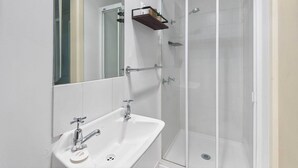 Une salle de bain avec un lavabo blanc, un miroir et une douche à parois de verre.