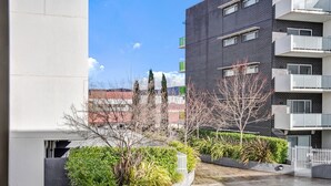 A modern building with balconies and a courtyard with plants.