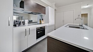 A modern kitchen with white cabinetry, stainless steel appliances, and a large island with a sink.