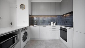 A modern kitchen with a built-in washer and dryer, a microwave, and a stove. - Chic 1-Bed Apartment In the Heart of Melbourne (Melbourne)