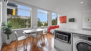 A modern kitchen with a dining area, large windows, and a washing machine. - Chic 1-Bed Apartment In the Heart of Melbourne (Melbourne)