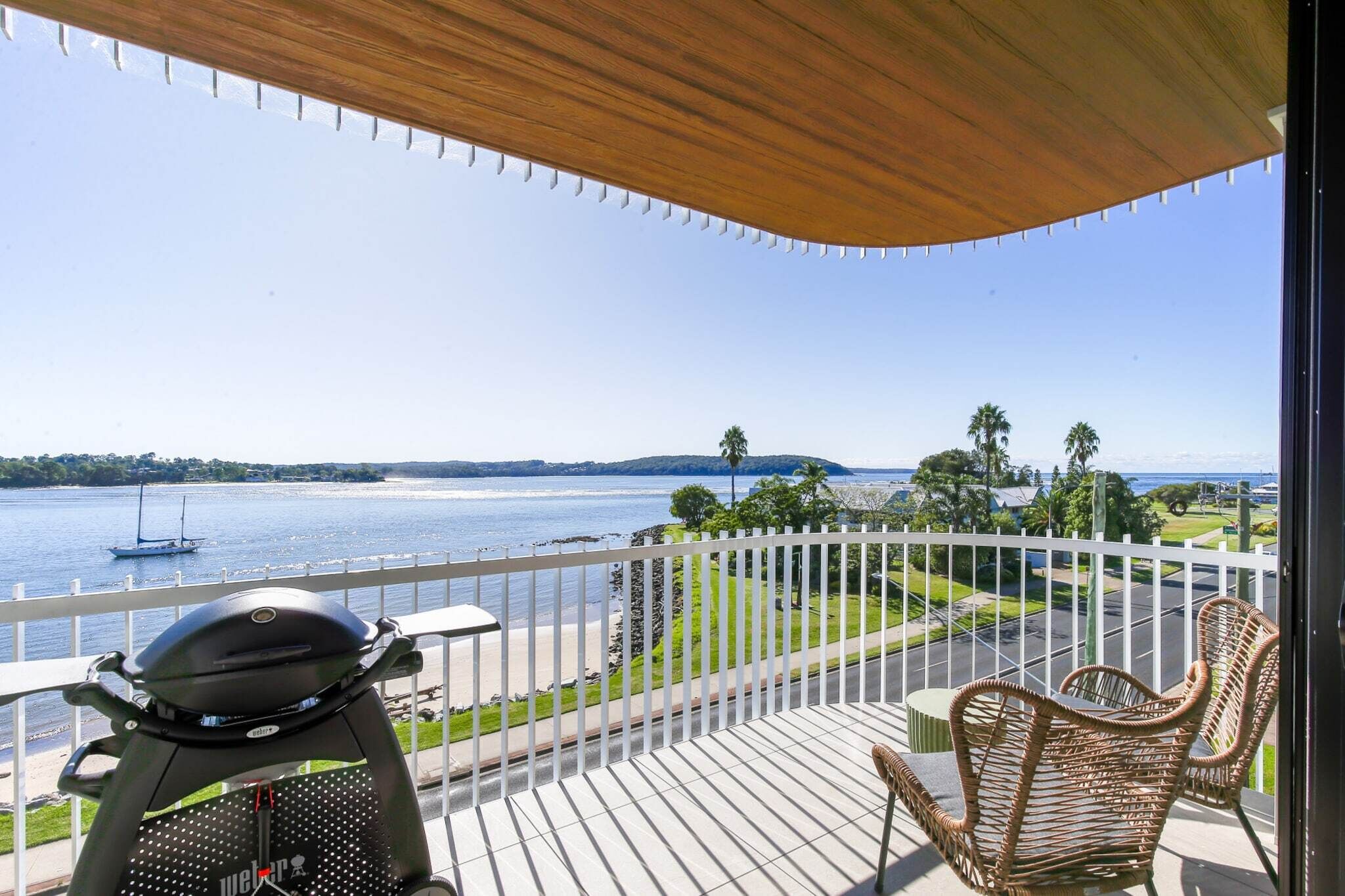 Een balkon met uitzicht op een meer, een boot en een strand.