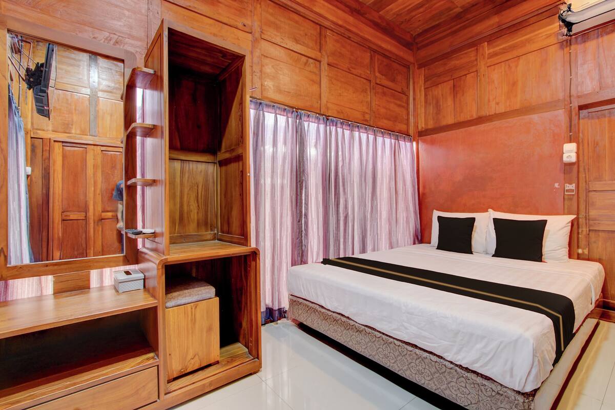 A wooden room with a bed, a wardrobe, and a desk.