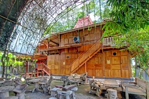 A wooden house with a red roof, a staircase, and a large fan. - OYO 95018 Anggrek Homestay Jogja Syariah (Sewon)
