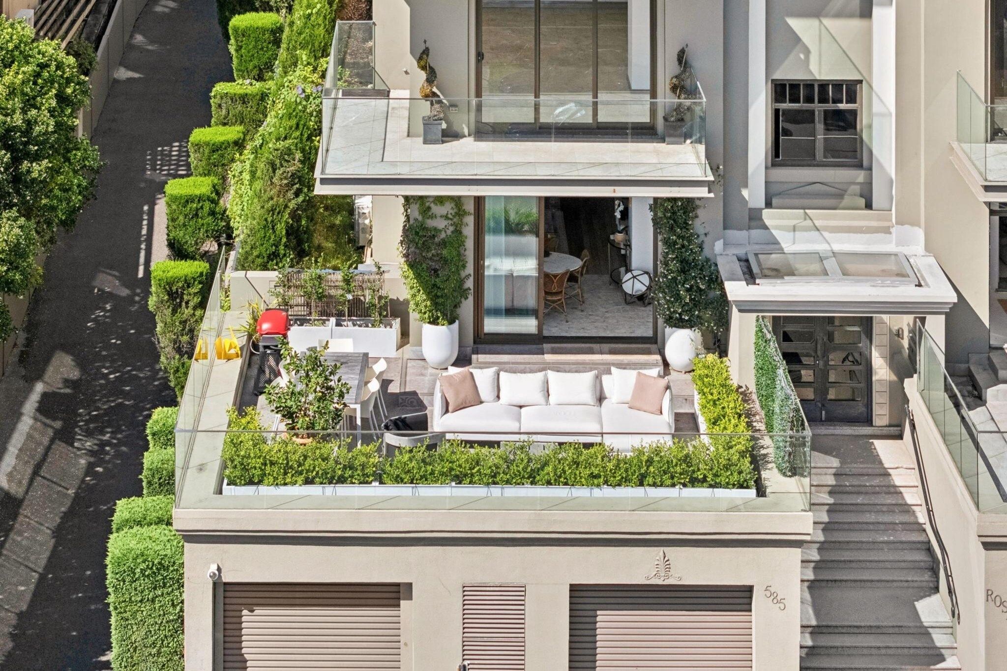 A modern residential building with a rooftop garden, a dining area, and a staircase leading to the entrance.