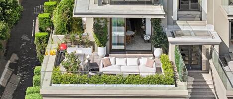 A modern residential building with a rooftop garden, a dining area, and a staircase leading to the entrance.