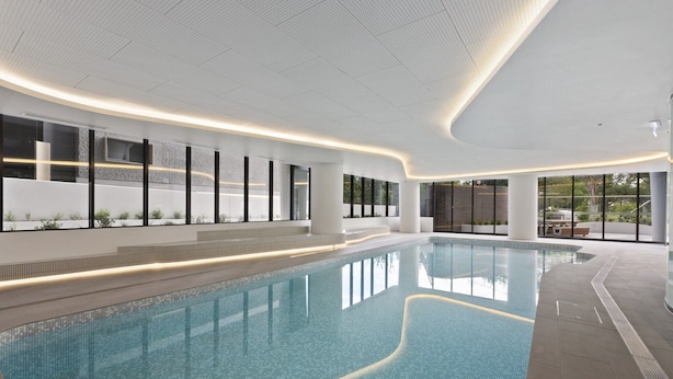 Une piscine intérieure moderne offrant une vue dégagée sur les environs, avec de grandes fenêtres et un sol carrelé et impeccable.