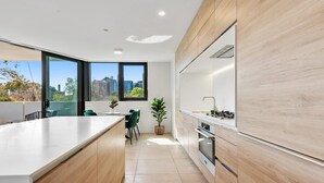 Une cuisine moderne dotée d’un grand îlot central, de meubles en bois et offrant une vue sur la ville.