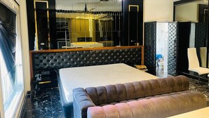 A modern bedroom with a large bed, a tufted headboard, a seating area, and a wardrobe. - THE PAD BY FRACSPACE (Hyderabad)