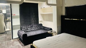 A bedroom with a bed, a sofa bed, a small round table, and a wardrobe. - THE PAD BY FRACSPACE (Hyderabad)