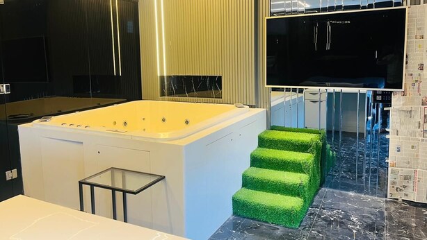 A modern bathroom with a large bathtub, a glass shower enclosure, and a green artificial grass step. - THE PAD BY FRACSPACE (Hyderabad)