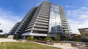 Un immeuble moderne à étages, doté de nombreux balcons et de grandes fenêtres.