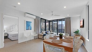 Un salon moderne avec un coin repas, de grandes fenêtres et une vue sur le paysage urbain.