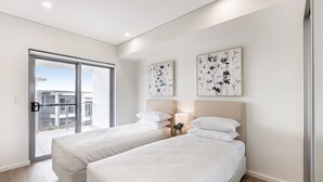 Una habitación de hotel moderna con dos camas individuales, una puerta corrediza al balcón y dos obras de arte con motivos florales en la pared.