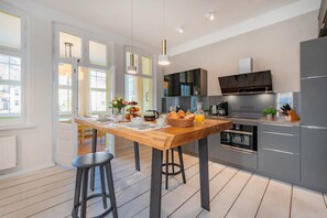 Eine moderne Küche mit einem Holztisch, gedeckt für das Frühstück, einem eingebauten Backofen und grauen Schränken.