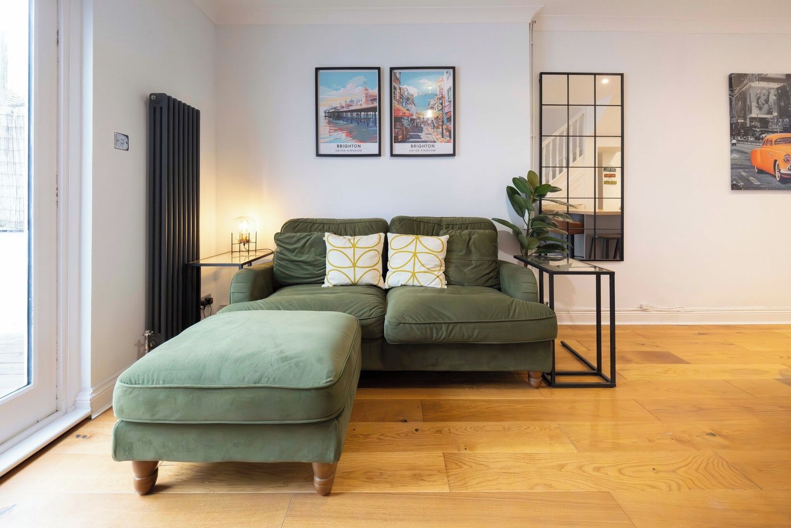 A modern living room with a sectional sofa, a small table, and two framed pictures on the wall.
