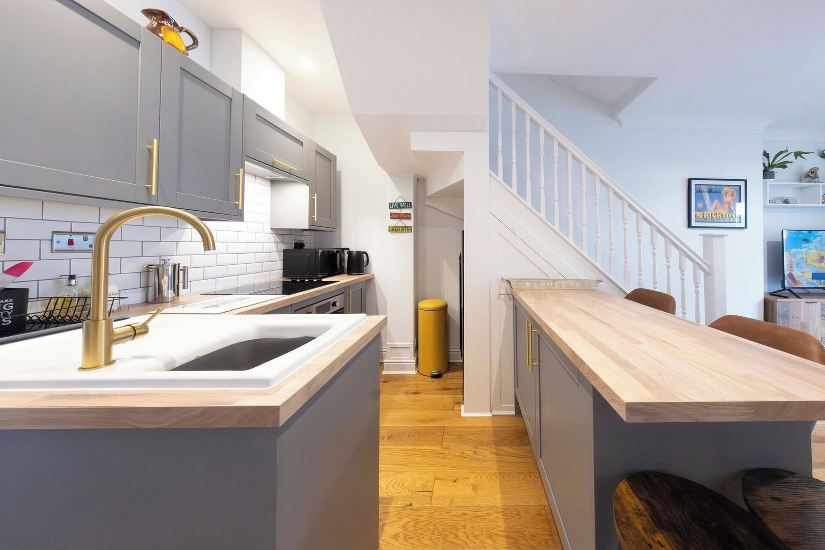 A modern kitchen with a central island, grey cabinets, and a wooden countertop.