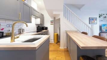 A modern kitchen with a central island, grey cabinets, and a wooden countertop.