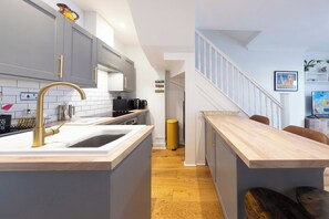 A modern kitchen with a central island, grey cabinets, and a wooden countertop. - Kemptown 2BR Coastal Retreat (Brighton and Hove)