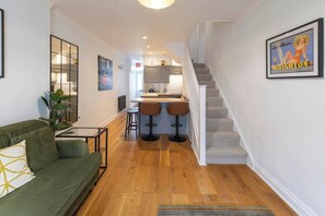 Une cuisine moderne dotée d’un îlot central, de tabourets de bar et d’un escalier menant à un niveau supérieur.