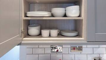 An open kitchen cabinet with dishes and glasses.