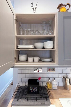An open kitchen cabinet with dishes and glasses.