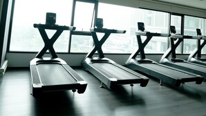 A gym with treadmills aligned in a row, large windows, and a ceiling with recessed lighting. - A charming one-bedroom a condo near the BTS (Bangkok)