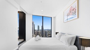 Habitació d'hotel moderna amb un llit gran, vista a la ciutat i una obra d'art emmarcada a la paret.